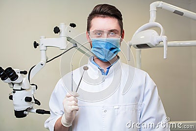 People, medicine, stomatology and healthcare concept - happy young male dentist with tools over medical office background Stock Photo