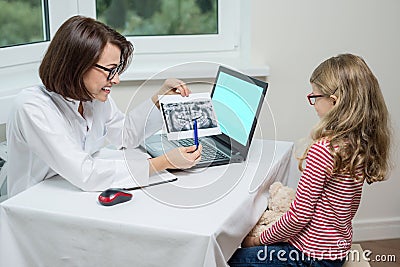 People, medicine, stomatology, technology and health care concept. Kid girl on consultation with dentist, looking at dental x-ray Stock Photo