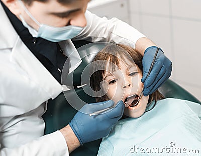 People, medicine, stomatology, technology and health care concept. Male dentist working with little girl in clinic. Stock Photo