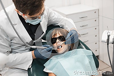 People, medicine, stomatology, technology and health care concept. Male dentist working with little girl in clinic. Stock Photo