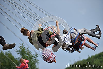 People in merry go round, swing ride, highland spinner Editorial Stock Photo