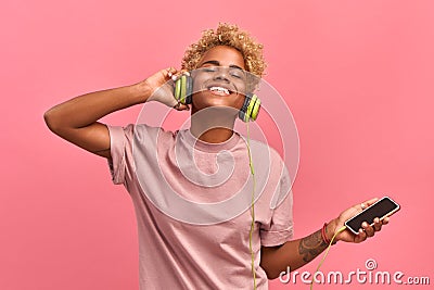 People, music, emotions concept. Delighted carefree female with Afro hairstyle dances in rhythm of melody, closes eyes Stock Photo