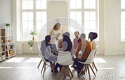 People participating in group therapy for social skill training in bright office Stock Photo