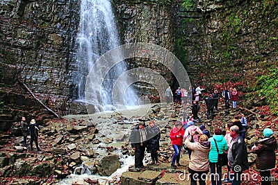 People are photographed against the background of the Manyavskii waterfall Editorial Stock Photo