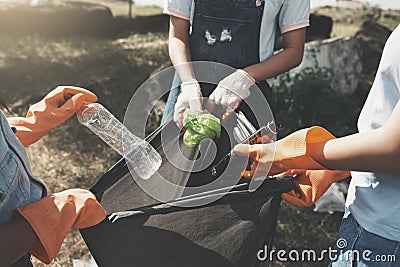 people picking up garbage and putting it in plastic black bag for cleaning at park Stock Photo