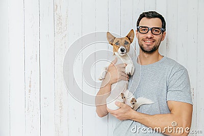 People, positiveness, animals and friendship concept. Happy unshaven male wears casual clothes, holds puppy, have walk Stock Photo