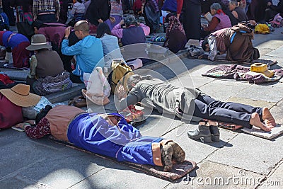 People praying in prostration in front of Jokhang temple in Lhasa on Barkhor square, Tibet Editorial Stock Photo