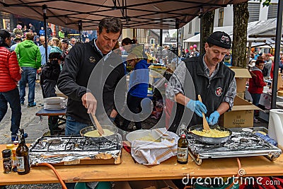 People during the preparation of traditional melted cheese at En Editorial Stock Photo