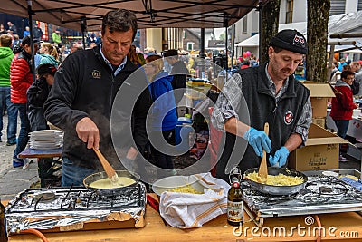 People during the preparation of traditional melted cheese at En Editorial Stock Photo