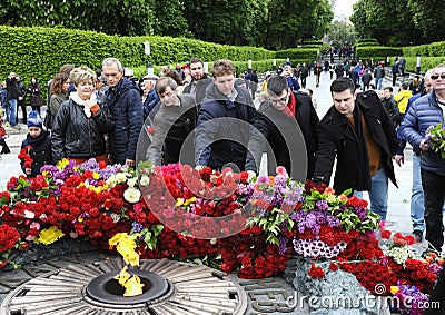 People putting flowers to the Eternal Flame in the Glory park, celebrating the Victory Day. Kyiv, Ukraine Editorial Stock Photo