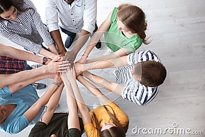 People putting hands together indoors Stock Photo