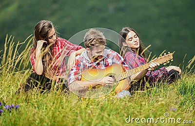 People relaxing on mountain top while handsome man playing guitar. Peaceful place. Melody of nature. Hiking tradition Stock Photo