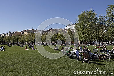 People relaxing in the New Holland island of the city, modern hipster place to spend weekend. Green lawn is full of families with Editorial Stock Photo