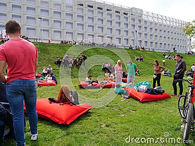 People rest on red inflatable mattresses placed on the green grass Editorial Stock Photo