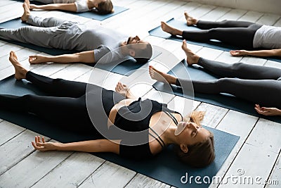 People resting after yoga workout lying in Shavasana Pose Stock Photo