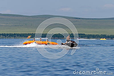 People ride a banana boat attached to a jet ski Editorial Stock Photo