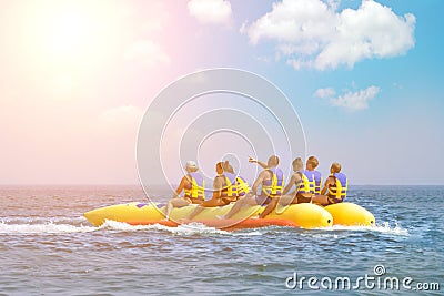 People ride on banana boat. Bright blue sea and blue sky with clouds. Happy vacation. Beach water sport. Hot active summer Editorial Stock Photo