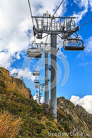 People ride on chair ski lift of Gorky Gorod mountain resort on autumn Caucasus mountains background. Sochi, Russia Stock Photo