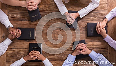 People`s Praying Hands On Holy Bible Stock Photo