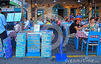 People sit in sidewalk street cafe in Chania waterfront on Crete Editorial Stock Photo