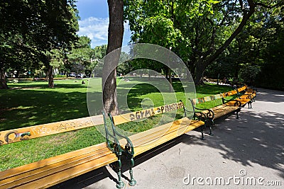 People sitting on bench, grass at Stadtpark, City Park in Vienna, Austria during summer season Editorial Stock Photo