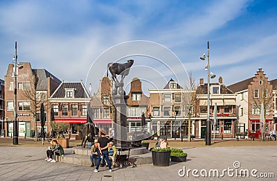 People sitting at the cow sculpture on the Koemarkt square in Purmerend Editorial Stock Photo