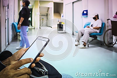 People sitting in front of the examination room and use a smartphones waitting to see a doctor in the hospital Stock Photo