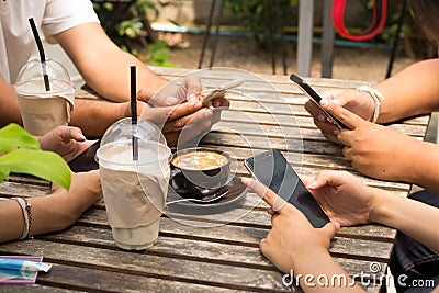 People are sitting on the phone and drinking coffee on a wooden table in a restaurant. Stock Photo