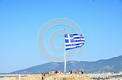 People are sitting under Greece flag in Acropolis. Editorial Stock Photo
