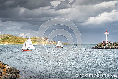 People on a small sailboats exiting Howth marina, with Irelands Eye island in the background Stock Photo
