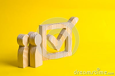 People stand near a wooden checkmark in a box on a yellow background. The concept of suffrage, voting in elections. Stock Photo