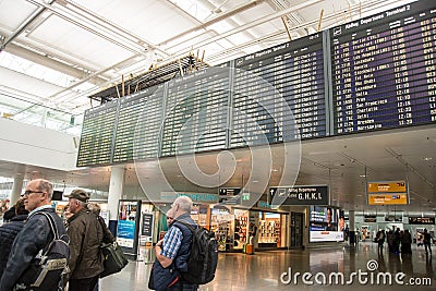 People stand under flight departure board Editorial Stock Photo