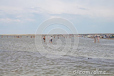 People stand in the water of Lake Shalkar. Shallow salt lake. Beach holidays in Kazakhstan. Editorial Stock Photo