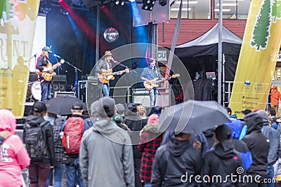 People standing in a crowd watching a band in the rain Editorial Stock Photo