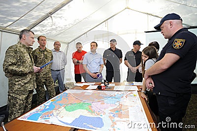 People standing in front of a table with maps. The headquarter of a firefighters, planning Editorial Stock Photo