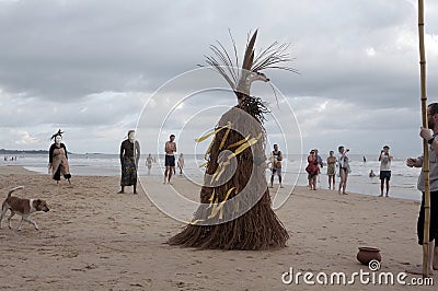 People and the Straw Scarecrow stand on a sandy beach on the ocean shore during a ceremony for good weather and good fishing Editorial Stock Photo