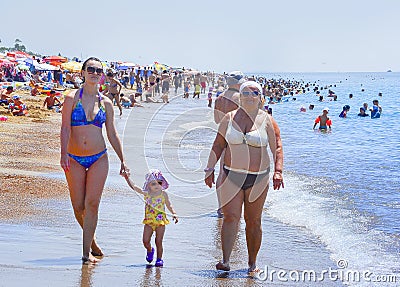 People sunbathe on the beach, swim in the sea. Editorial Stock Photo