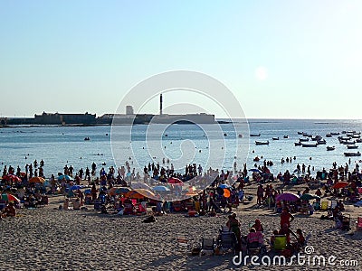 People sunbathing at sunset on the beach of La Caleta in the bay of Cadiz, Andalusia. Spain. Editorial Stock Photo