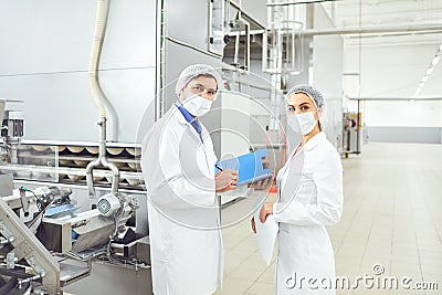 People technologists in masks at food factory. Stock Photo