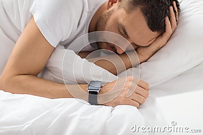 Close up of man with smart watch sleeping in bed Stock Photo