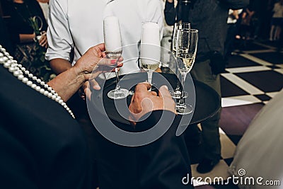 people toasting with champagne glasses at wedding reception, waiter serving on tray champagne drinks, celebration catering Stock Photo