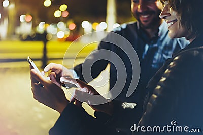 People together pointing finger on screen smartphone on background bokeh light in night atmospheric city, group adult hipsters Stock Photo