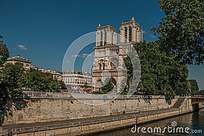 People, tree-lined Seine River and gothic Notre-Dame Cathedral at Paris. Editorial Stock Photo