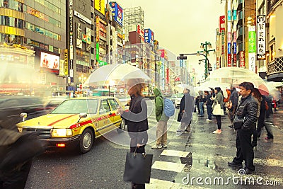 People with umbrellas under the rain in the bustling neighborhood of Shinjuku, Tokyo Editorial Stock Photo