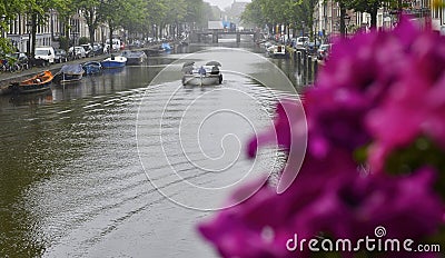 People under umbrellas enjoy boating on the Amsterdam canal. Editorial Stock Photo