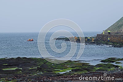 People in uniform on the shore and in the boat conduct rescue operations on the seacoas Stock Photo