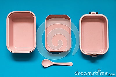 Empty pink bento lunch box with spoon on blue background Stock Photo