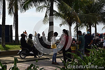 People wait on queue on bay walk to view the artificially face lifted beach coast line dumped with white dolomite sand. silhouett Editorial Stock Photo