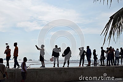 People wait on queue on bay walk to view the artificially face lifted beach coast line dumped with white dolomite sand. silhouette Editorial Stock Photo