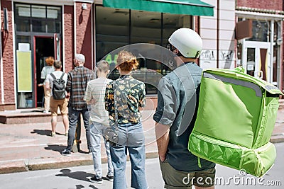 People waiting, standing in line, respecting social distancing to enter takeout restaurant or to collect purchases from Stock Photo